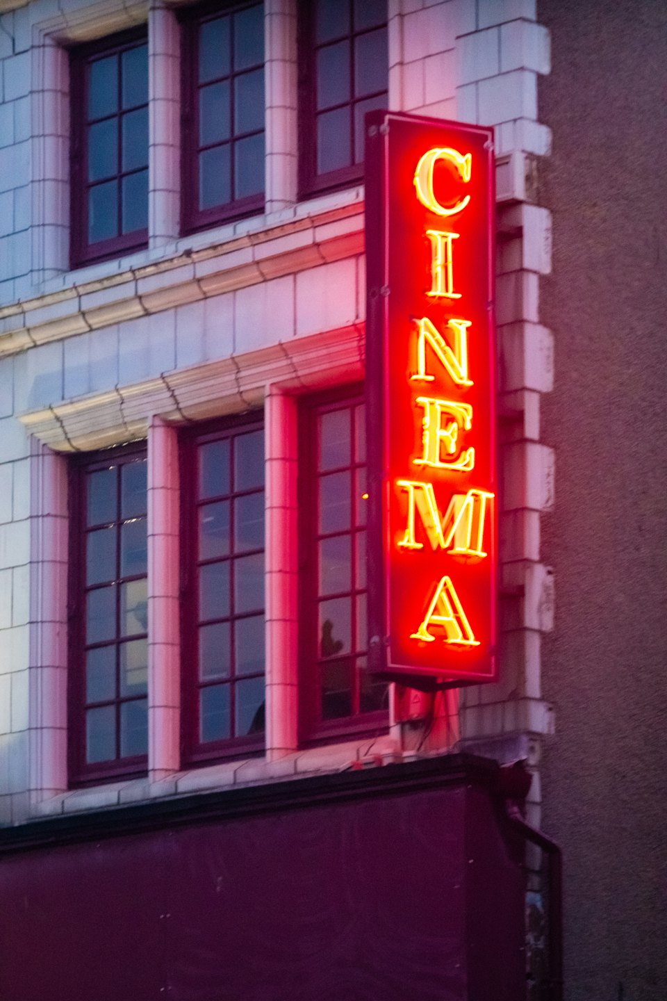Insegna al neon CINEMA rossa vintage su un vecchio edificio al crepuscolo.