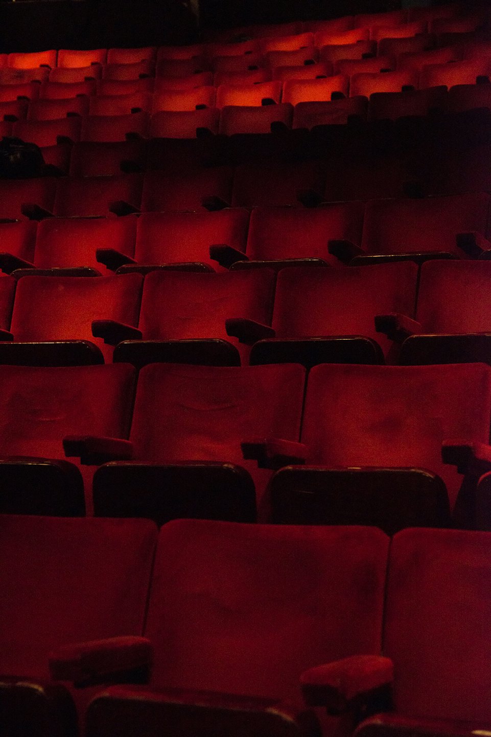 File di sedili vuoti in velluto rosso in un auditorium.